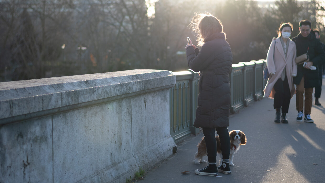 A woman who is traveling with her dog takes it out for a walk in Paris.