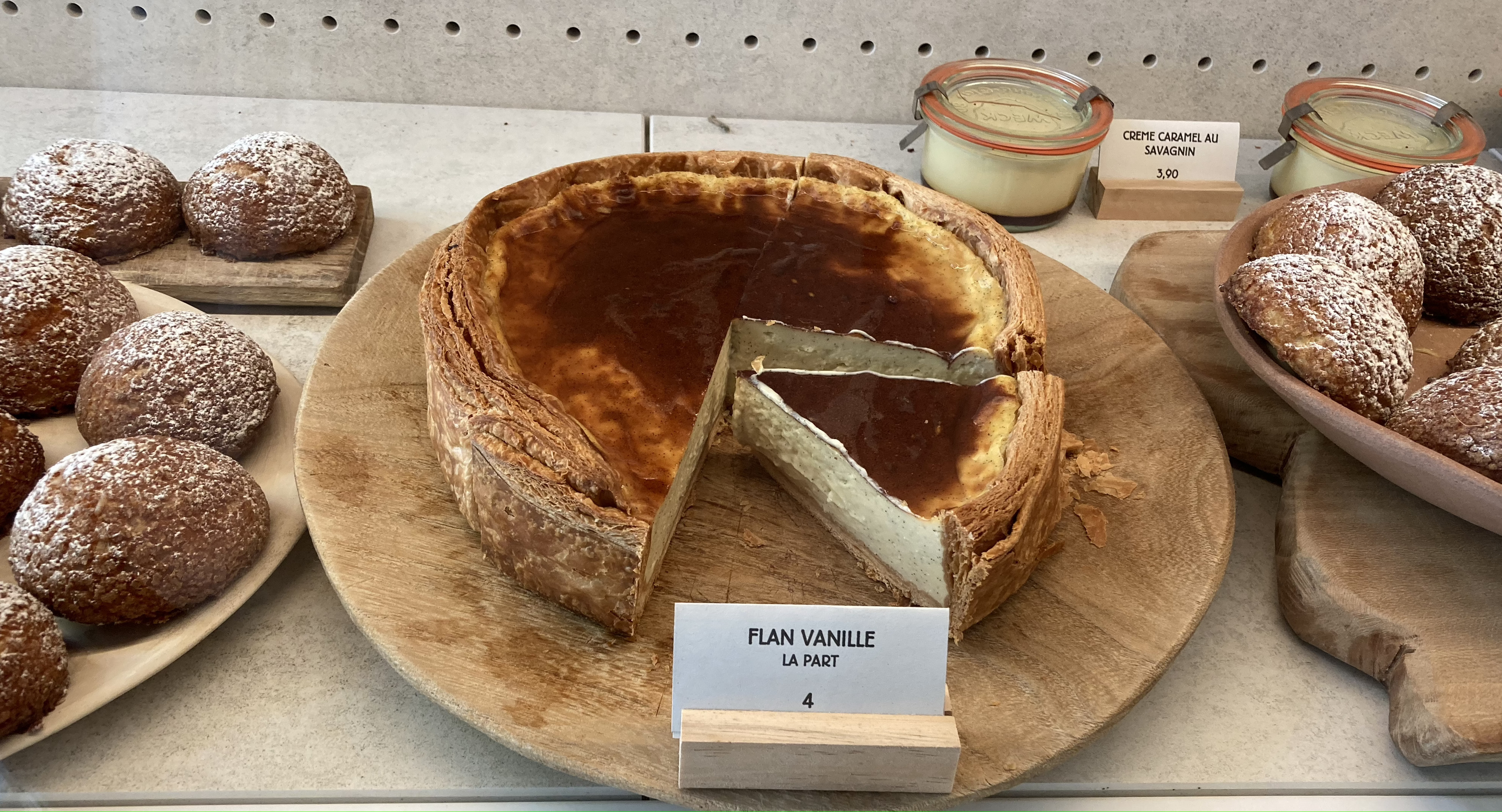A whole, creamy vanilla flan with one piece missing in the vitrine of Tapisserie in the the 7th arrondissement.
