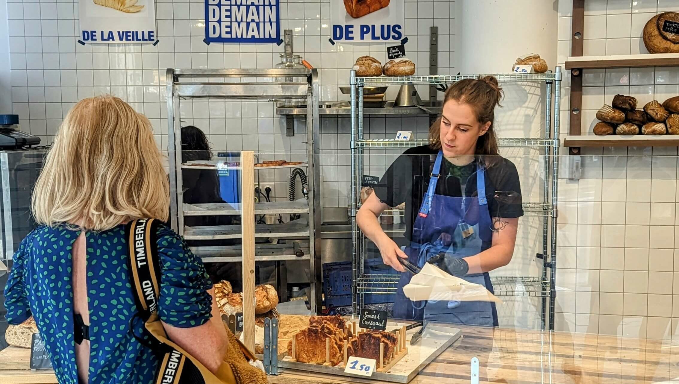 An employee at Paris' first zero waste bakery Demain serves their signature smash croissants to a client.