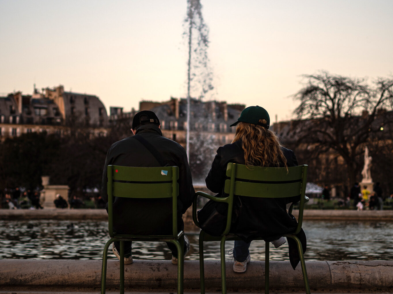 A couple sitting in front of the fountain in the Tuileries gardens in the 1st arrondissement in Paris.