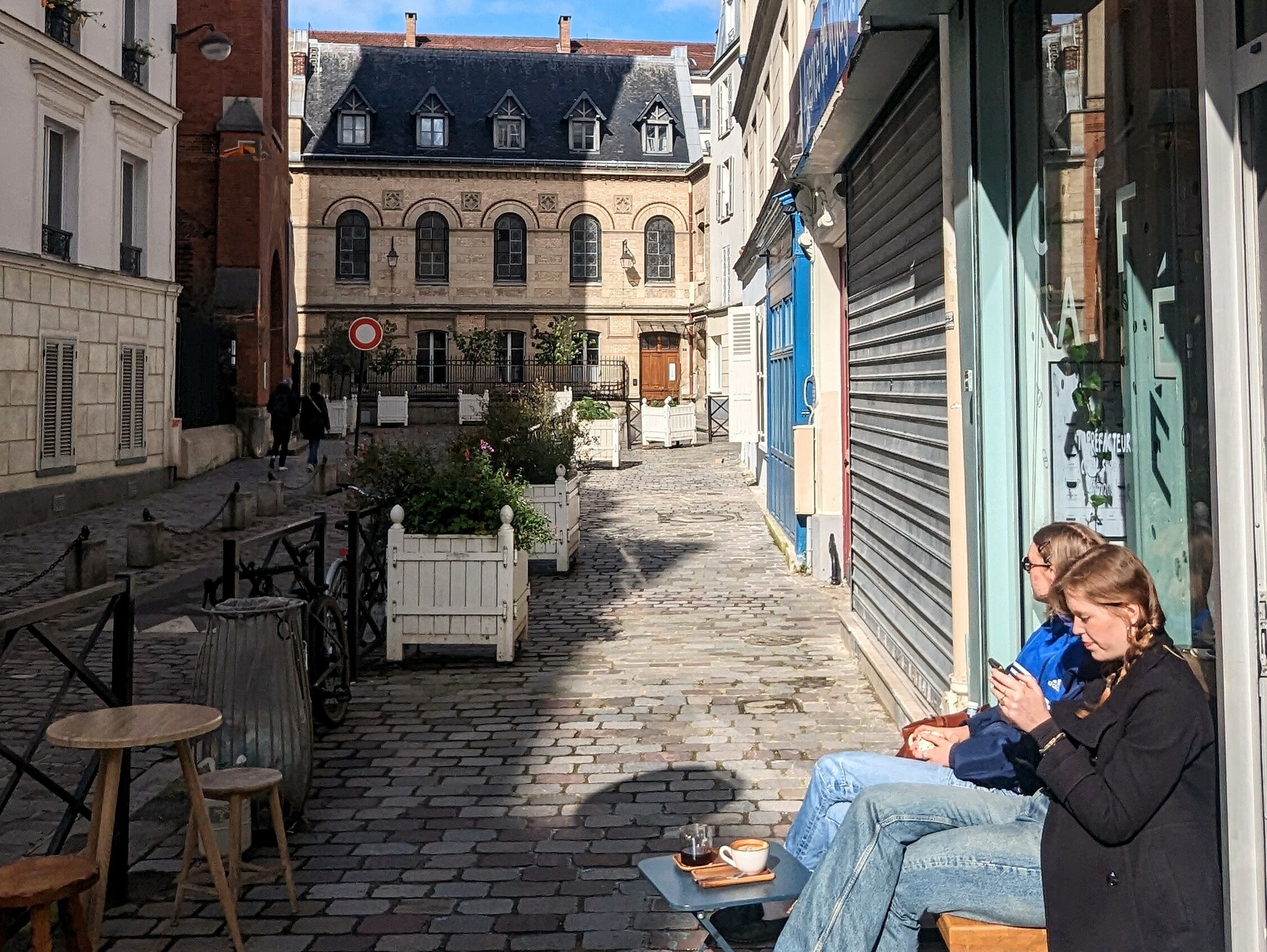 Two women enjoying a coffee in the sun in front of Canopi Coffee in the 17th arrondissement.