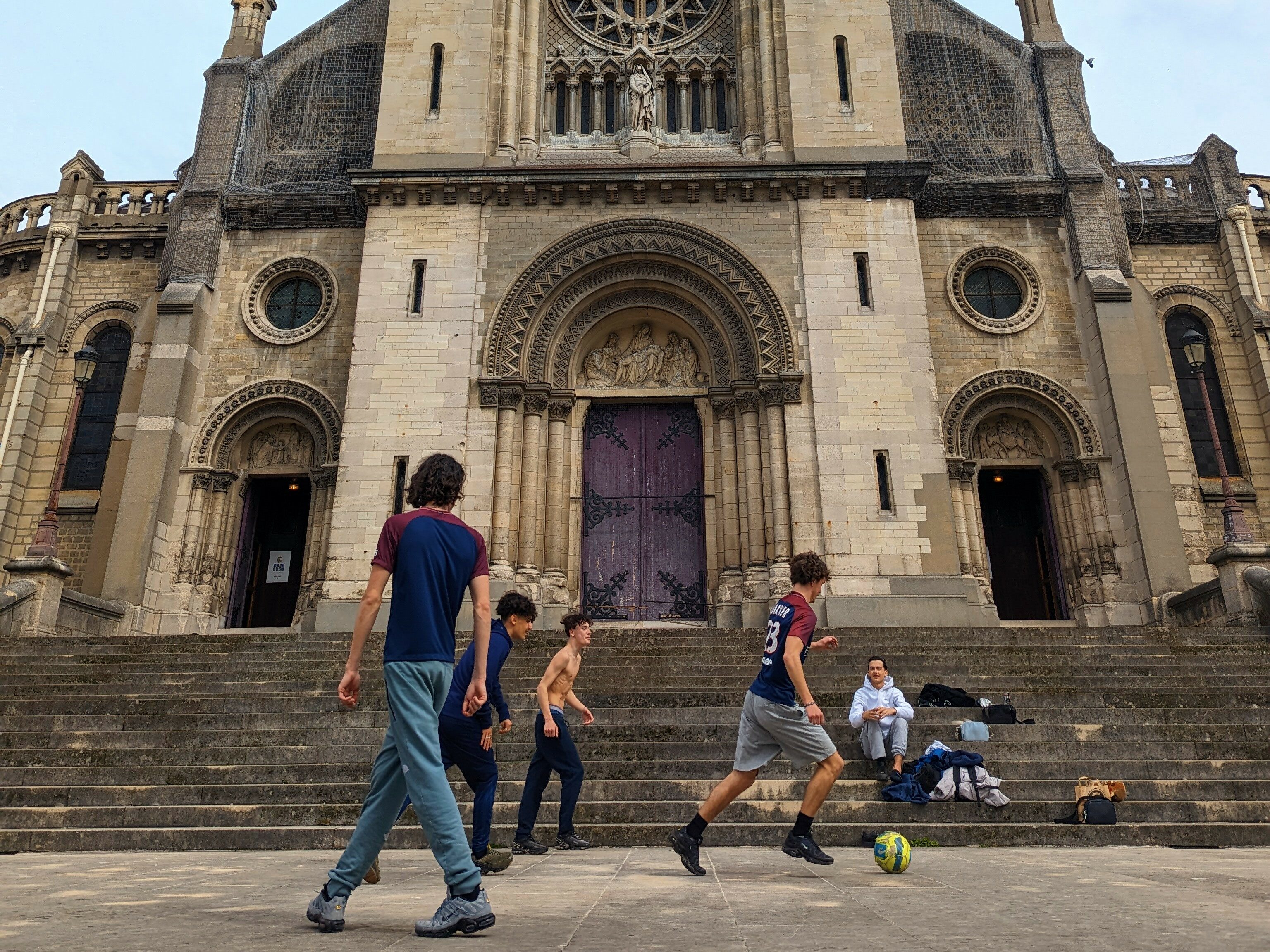 Five boys playing soccer in front of a church in the Ménilmontant district in the 20th arrondissement.