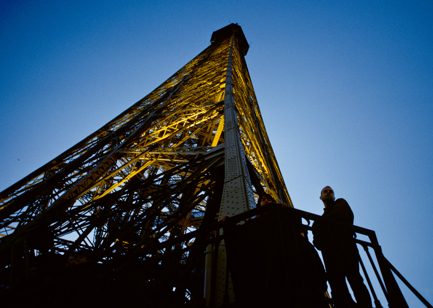 Two people standing on the platform of the lit up Eiffel Tower.