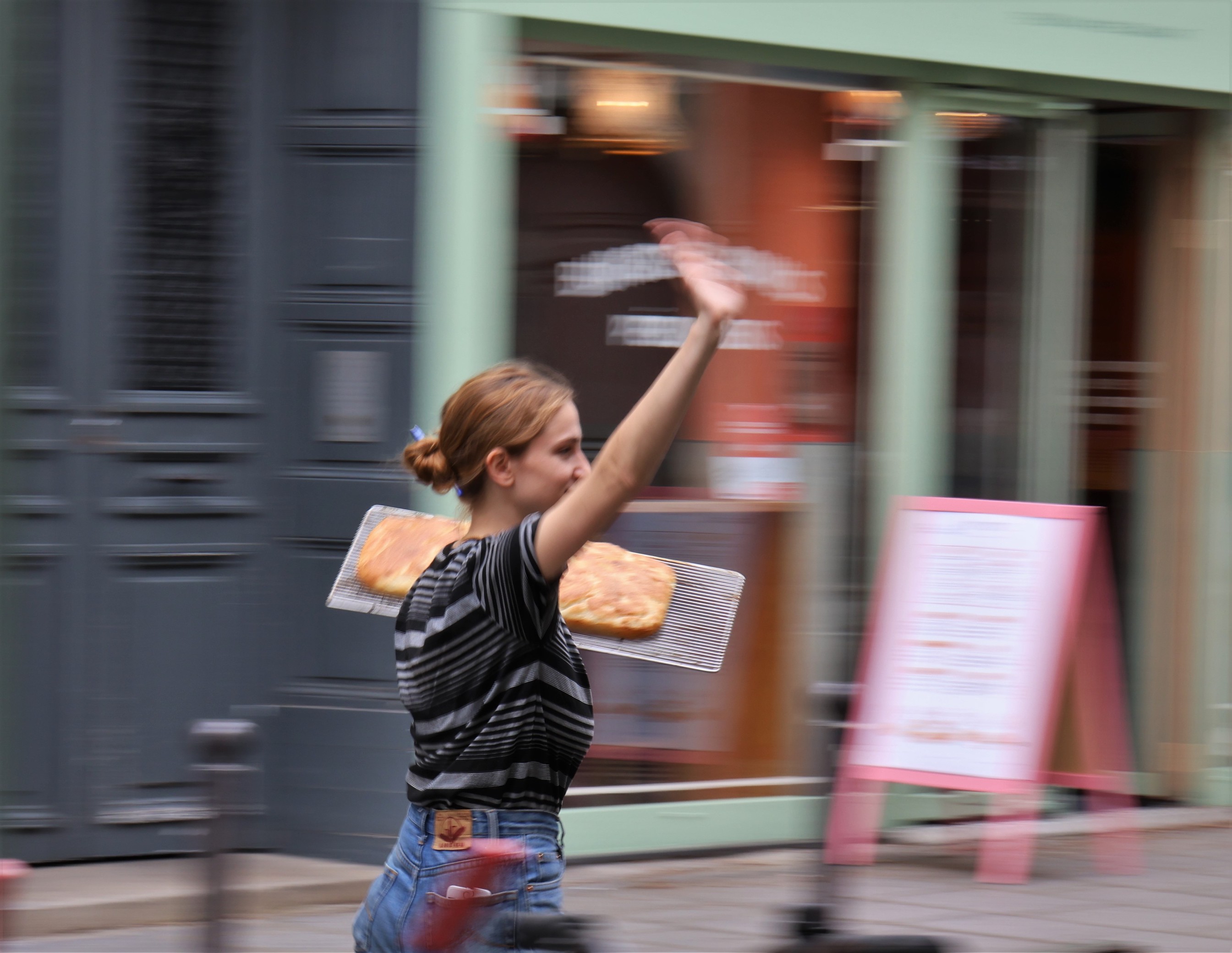 A Parisian woman carries a tray of freshly baked bread from Boulangerie du Sentier to a restaurant.
