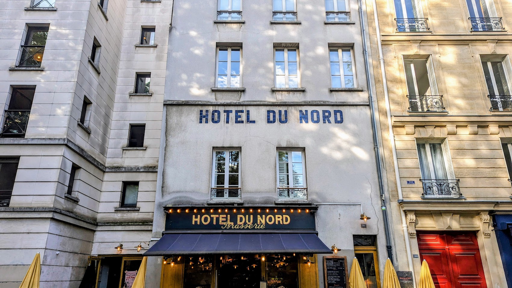 The blue awnings and white facade of the Hotel du Nord by the Canal Saint-Martin.